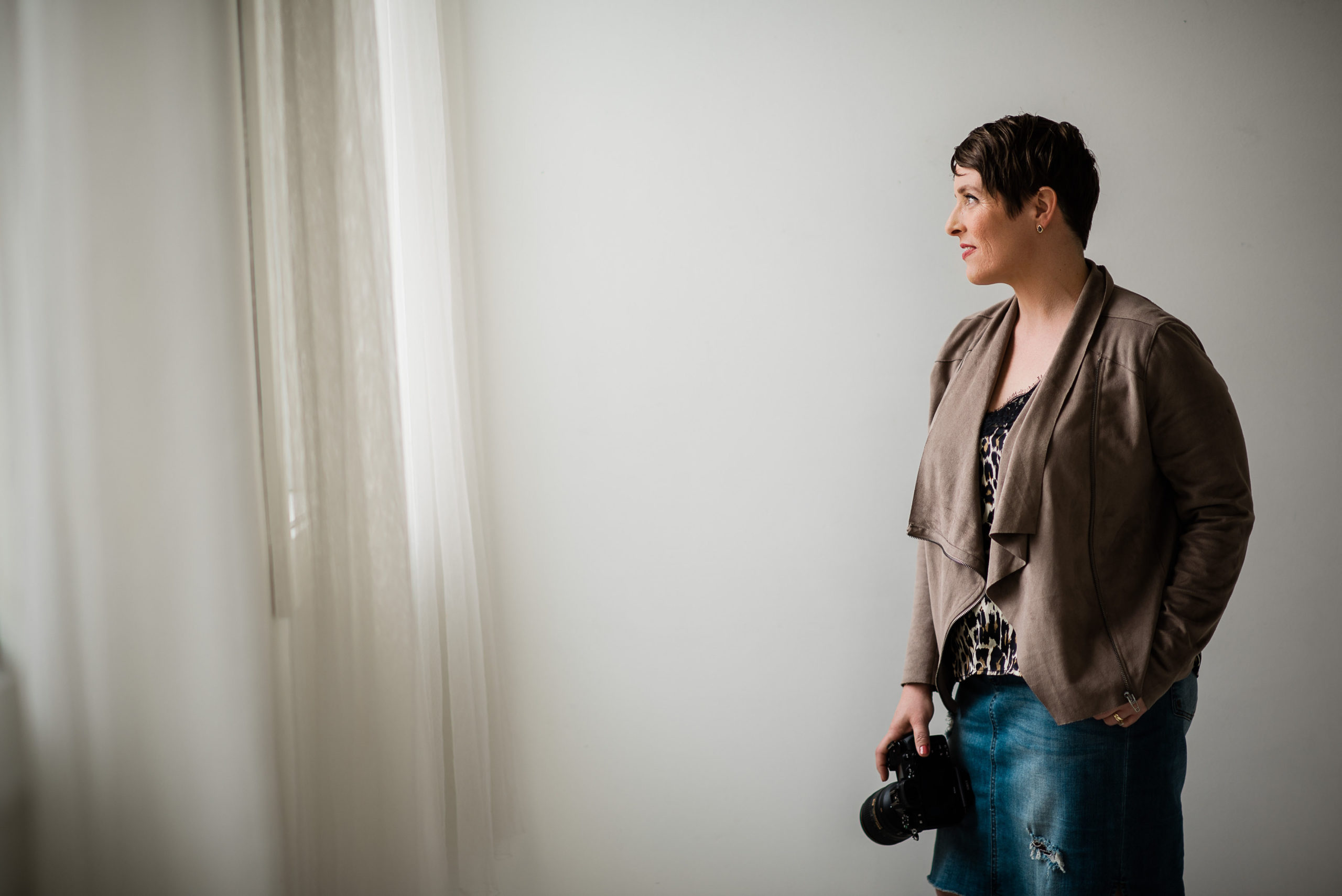 Lara Grauer looking out window with camera