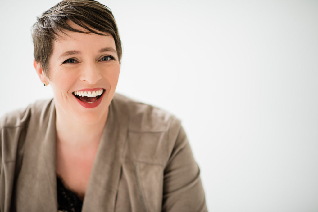 Woman posing for headshot with a very big smile.