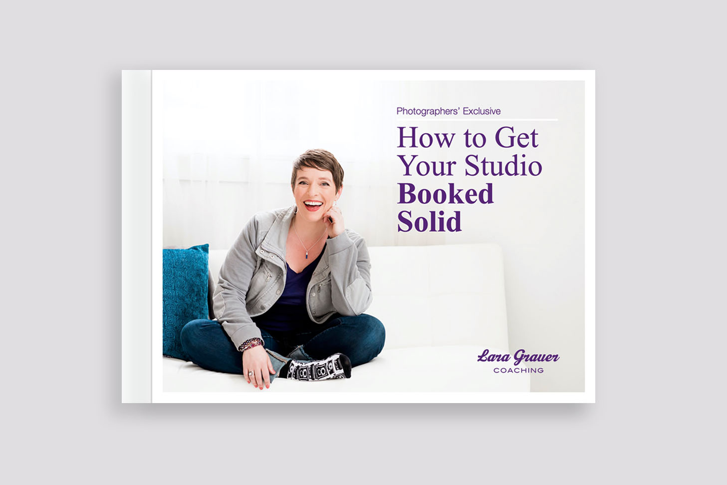 Book cover. Woman smiling sitting cross-legged on a white sofa. Included text that reads, How to Get Your Studio Booked Solid. Lara Grauer Coaching.
